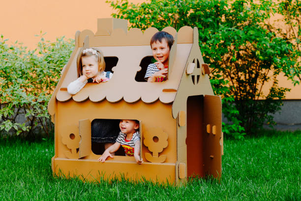 Children are playing in cardboard kid house. Child having fun outdoors